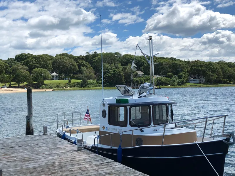Slide: The Image of 2013 Ranger Tugs R-21 EC docked by a scenic shoreline under a partly cloudy sky. - 3