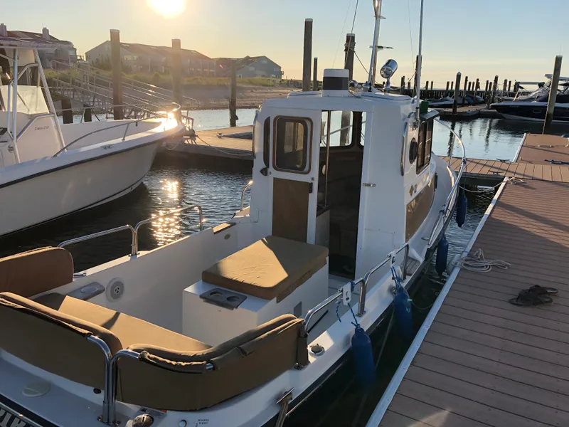Slide: The Image of 2013 Ranger Tugs R-21 EC docked at sunset, showcasing its compact design and cozy seating. - 6