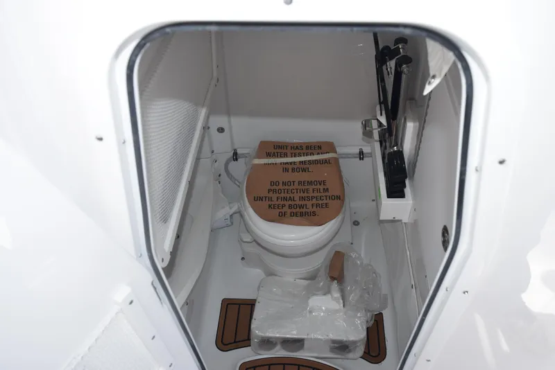 Slide: The Image of 2025 Sea Hunt Ultra 265 SE boat bathroom with toilet and protective cover. - 15