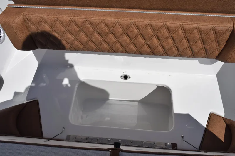 Slide: The Image of 2025 Sea Hunt Ultra 265 SE boat interior with brown diamond-stitched seating and white storage compartment. - 21