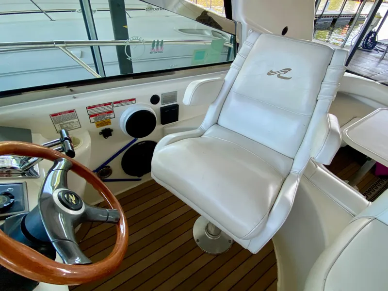 Slide: The Image of Captain's chair and helm of 1997 Sea Ray 400 Sundancer yacht, featuring wood accents and controls. - 13