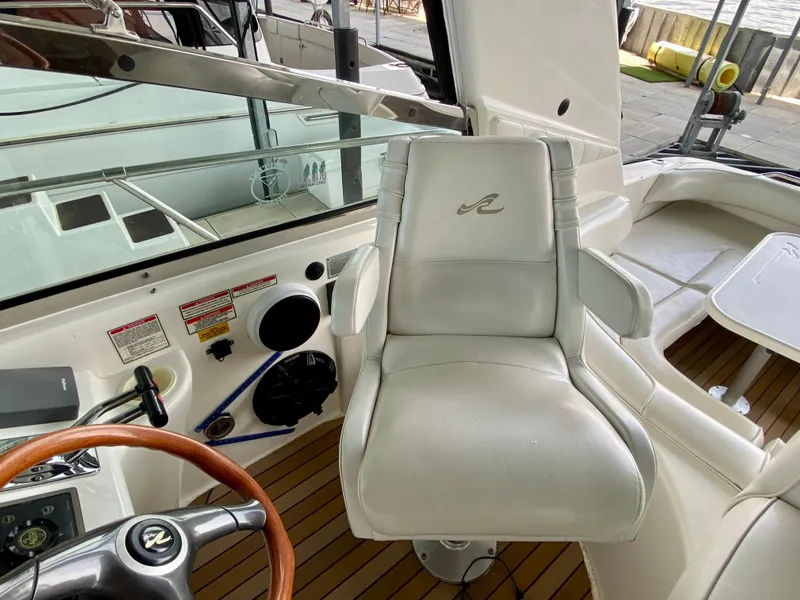 Slide: The Image of Captain's chair on 1997 Sea Ray 400 Sundancer yacht, featuring sleek white design and wooden accents. - 14