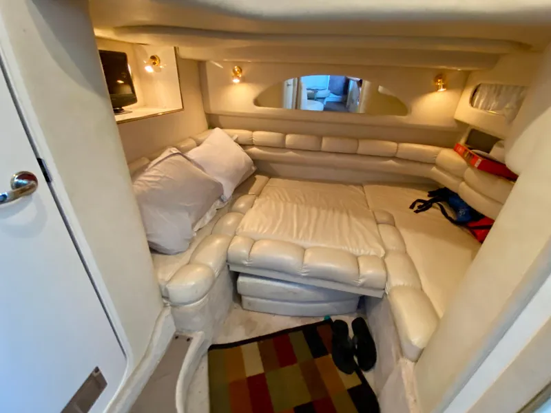 Slide: The Image of 1997 Sea Ray 400 Sundancer cabin with plush seating, cozy bed, and ambient lighting. - 23
