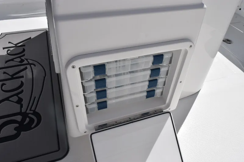 Slide: The Image of 2025 BlackJack 256 Coastal boat storage compartment with organized tackle boxes. - 21