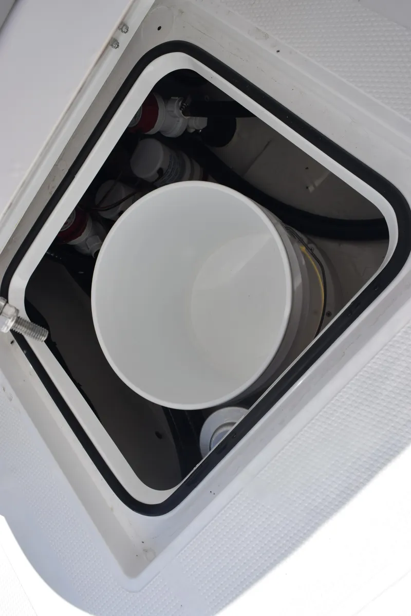 Slide: The Image of 2025 BlackJack 256 Coastal boat storage compartment with white bucket inside. - 23