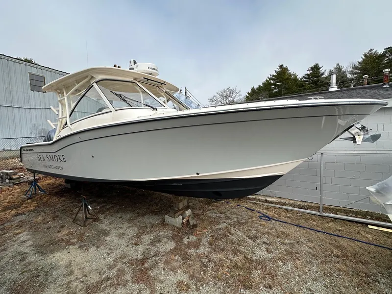 Slide: The Image of 2022 Grady-White 325 Freedom boat on land, side view, near building and trees. - 0