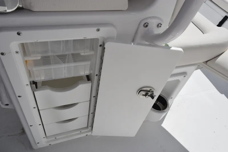 Slide: The Image of 2025 Sea Hunt Ultra 235 SE boat storage compartment with open door and organized drawers. - 17