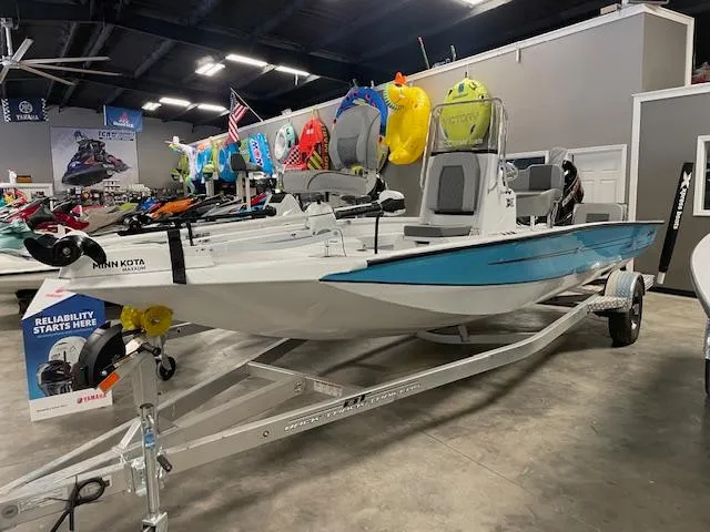 Slide: The Image of 2025 Xpress Hyper Lift H20 Bay boat on display in a showroom with colorful accessories. - 1