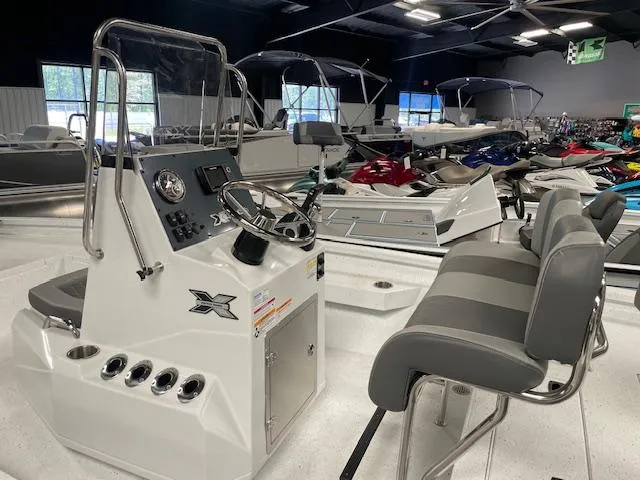 Slide: The Image of 2025 Xpress Hyper Lift H20 Bay boat interior with steering console and seating in showroom. - 7