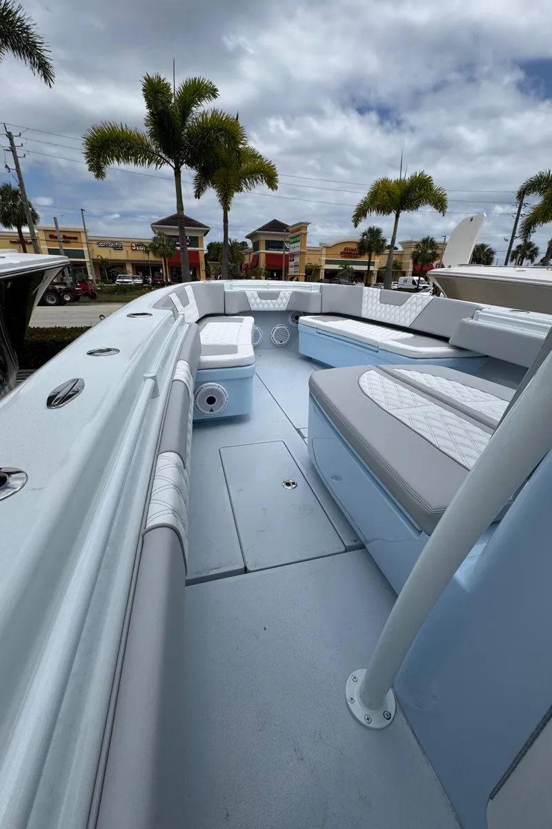 Slide: The Image of 2025 Contender 35 ST boat interior with seating, palm trees, and cloudy sky. - 10