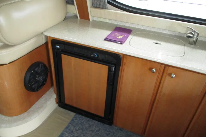 Slide: The Image of 2004 Meridian 340 yacht interior with kitchenette, featuring sink, fridge, and wooden cabinetry. - 22