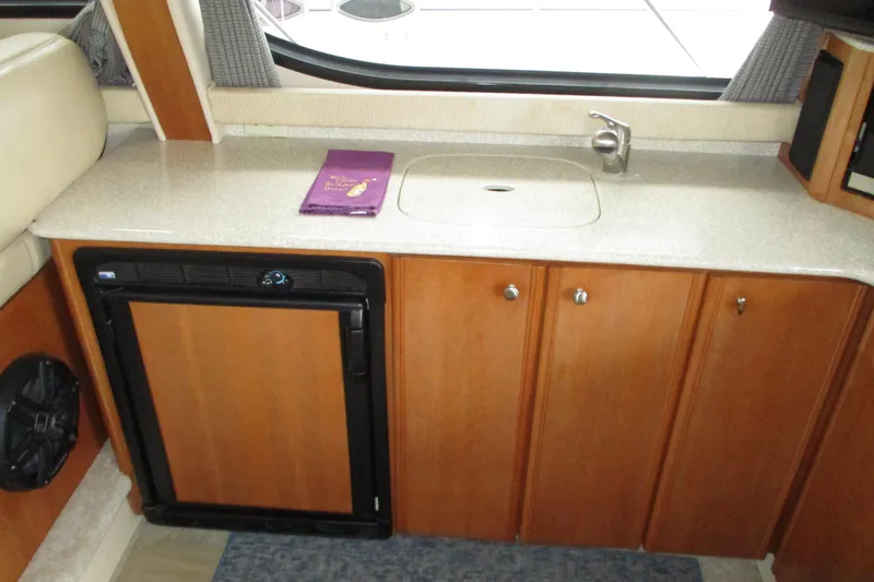 Slide: The Image of 2004 Meridian 340 yacht interior with kitchenette, featuring sink, countertop, and mini fridge. - 23