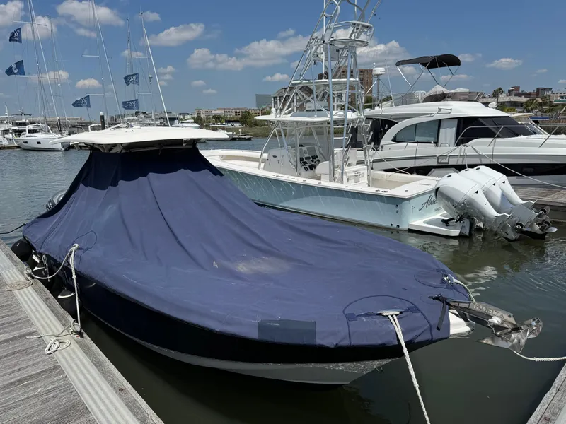 Slide: The Image of 2012 Scout 262 XSF boat covered with blue tarp, docked in marina. - 18