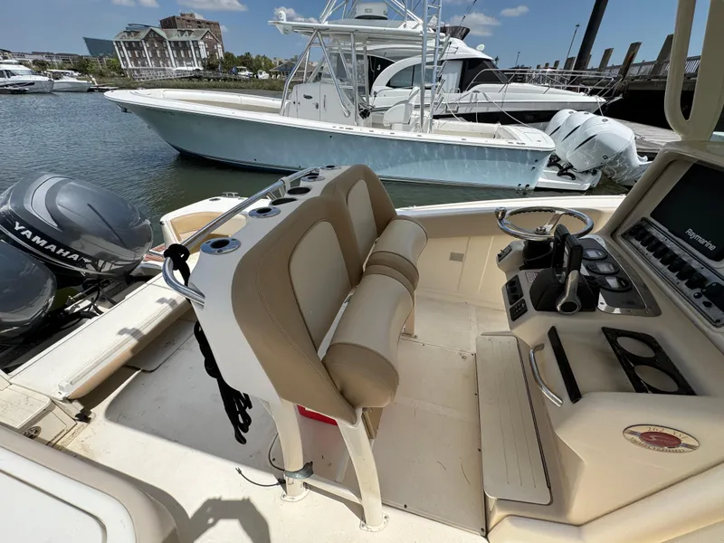 Slide: The Image of 2012 Scout 262 XSF boat interior with helm, seating, and Yamaha engines at marina. - 9