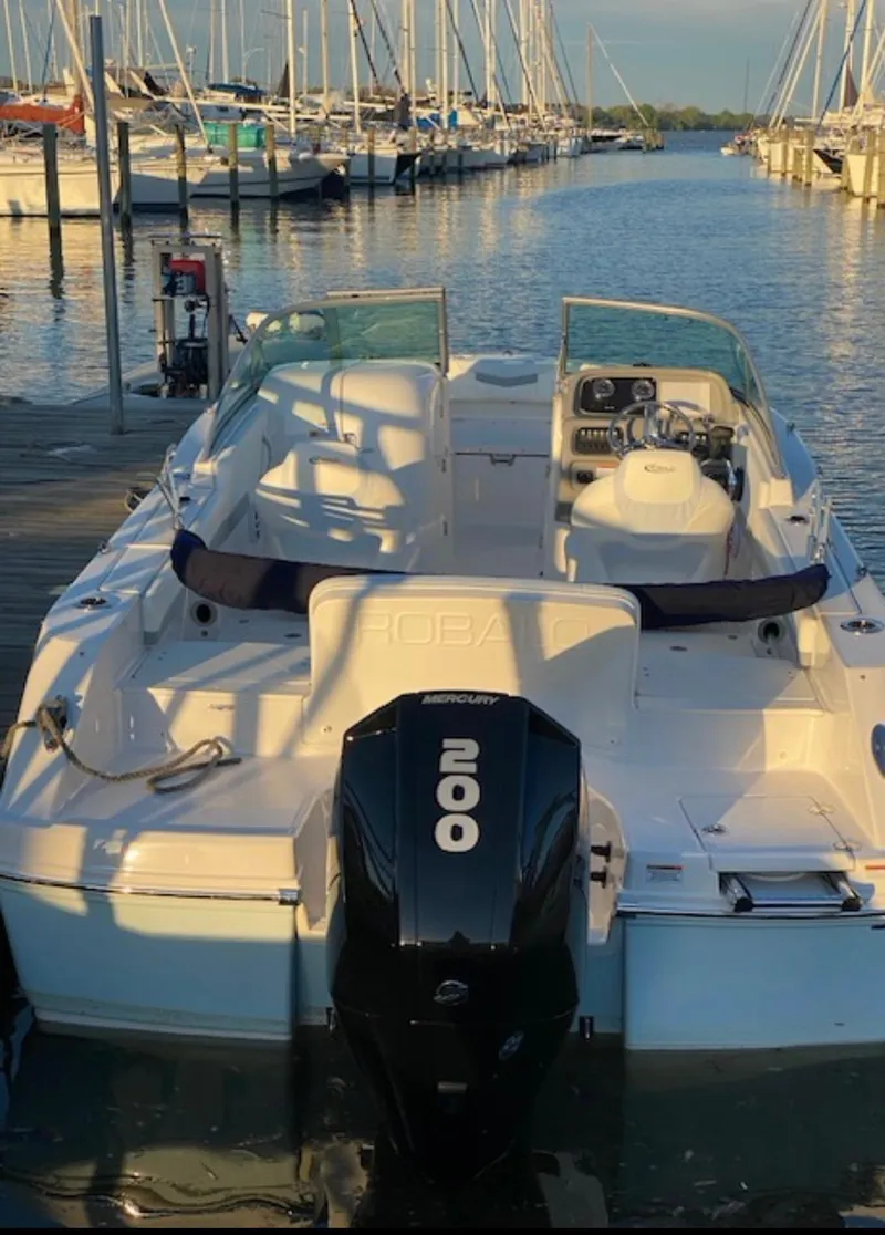 Slide: The Image of 2022 Robalo R207 Dual Console boat docked at marina with outboard motor. - 2