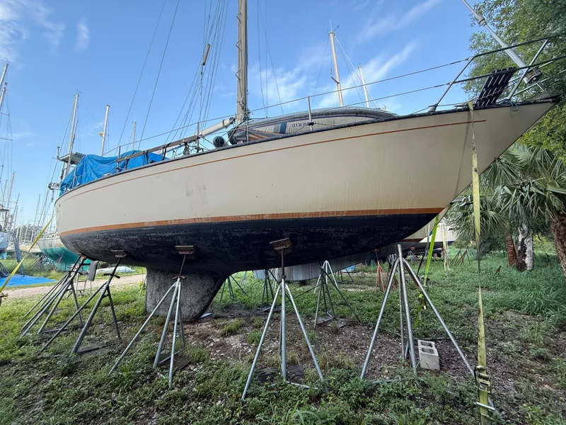 Slide: The Image of 1981 S2 11A sailboat on stands, surrounded by grass and trees, under a clear blue sky. - 22