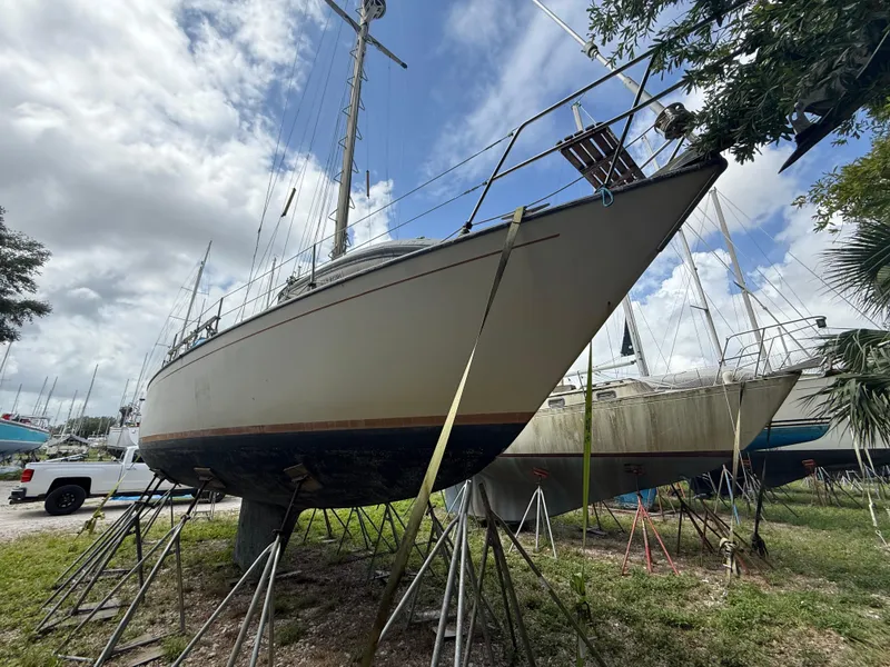 Slide: The Image of 1981 S2 11A sailboat on stands, cloudy sky, grassy boatyard setting. - 3