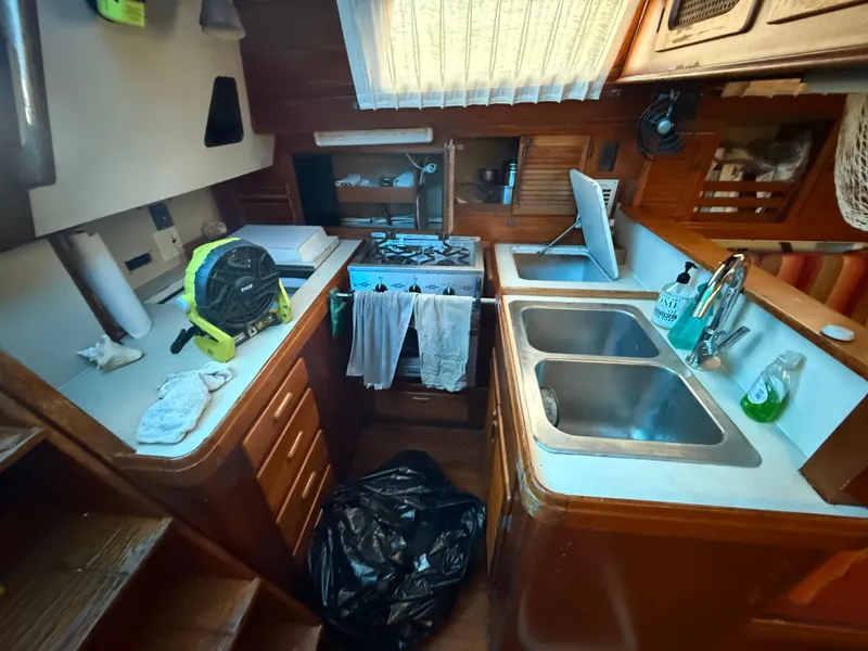 Slide: The Image of Compact 1981 S2 11A sailboat kitchen with dual sinks, stove, and wooden cabinetry. - 38