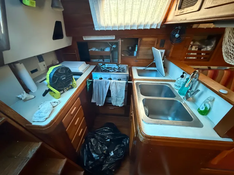 Slide: The Image of Compact 1981 S2 11A sailboat kitchen with dual sinks, stove, and wooden cabinetry. - 39