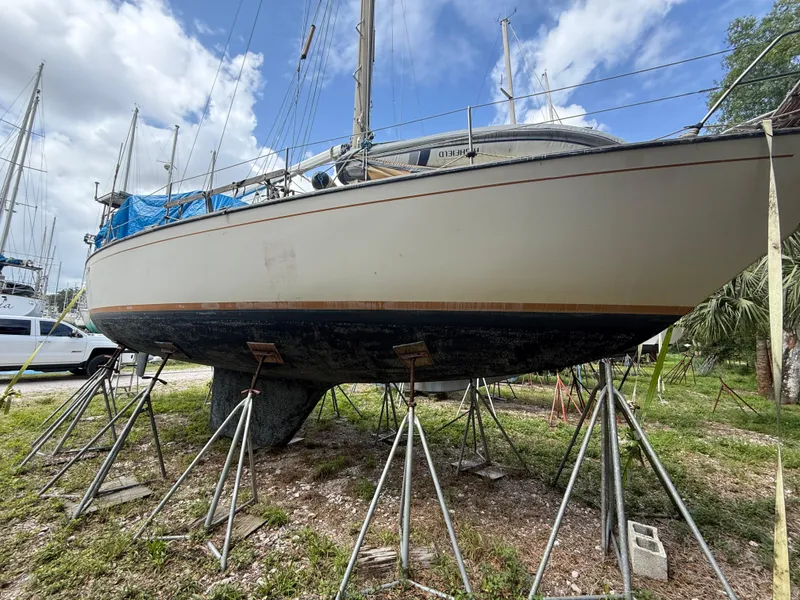 Slide: The Image of 1981 S2 11A sailboat on stands, under a partly cloudy sky. - 4