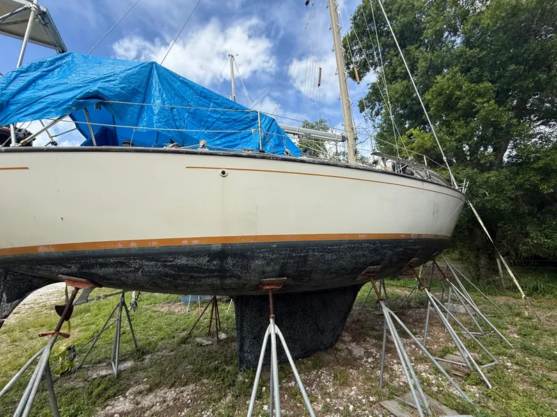 Slide: The Image of 1981 S2 11A sailboat on stands, covered with blue tarp, outdoors. - 5