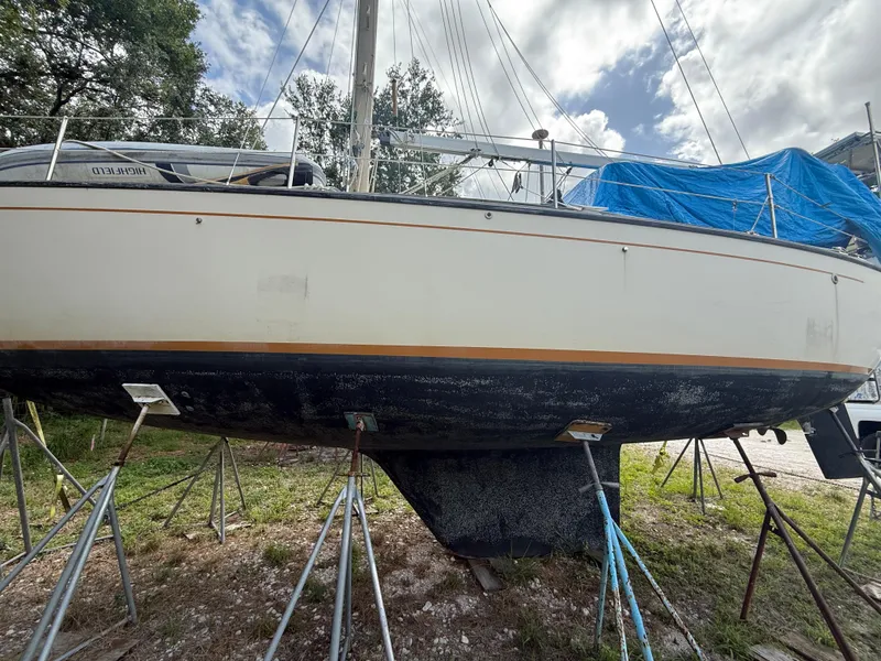 Slide: The Image of 1981 S2 11A sailboat on stands, partially covered, with trees and sky in background. - 9