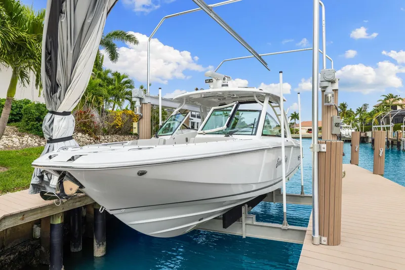 Slide: The Image of 2022 Boston Whaler 320 Vantage boat docked on a lift, surrounded by tropical scenery. - 0