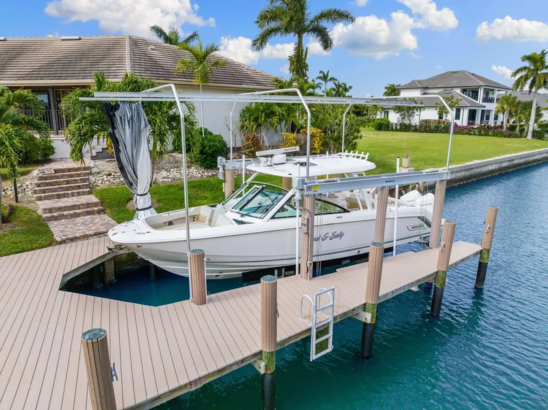 Slide: The Image of 2022 Boston Whaler 320 Vantage docked by waterfront home, surrounded by lush greenery. - 1