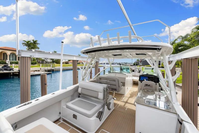 Slide: The Image of 2022 Boston Whaler 320 Vantage boat interior with seating, docked by a canal. - 12