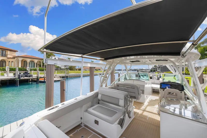 Slide: The Image of 2022 Boston Whaler 320 Vantage boat interior with seating and canopy, docked by waterfront homes. - 13