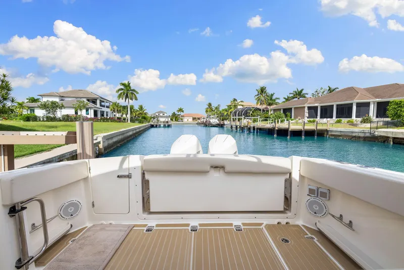 Slide: The Image of Boston Whaler 320 Vantage 2022 on a serene waterfront with palm trees and blue sky. - 14