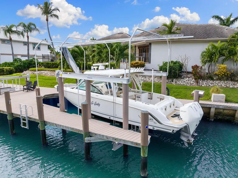 Slide: The Image of 2022 Boston Whaler 320 Vantage docked by a waterfront home with palm trees. - 2