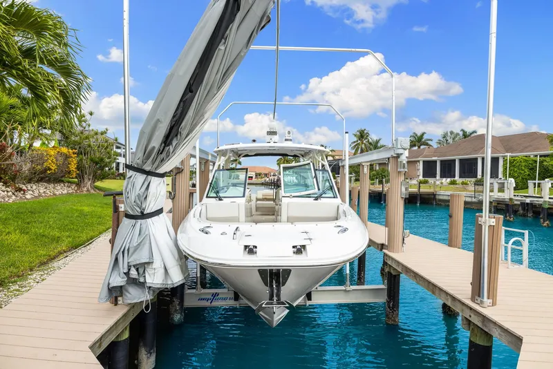 Slide: The Image of 2022 Boston Whaler 320 Vantage docked on a lift, surrounded by clear blue water and palm trees. - 5