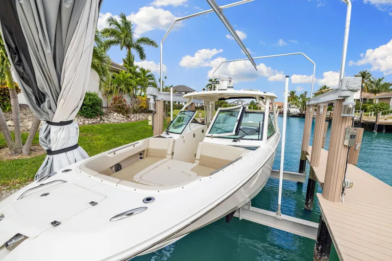 Slide: The Image of 2022 Boston Whaler 320 Vantage docked in a scenic waterfront setting. - 6