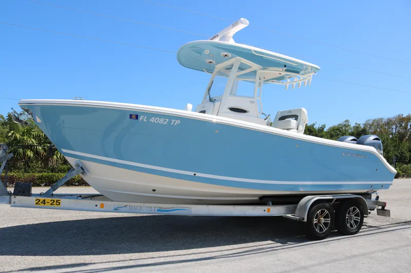 Slide: The Image of 2023 Cobia 240 CC boat on trailer, light blue hull, parked outdoors. - 0