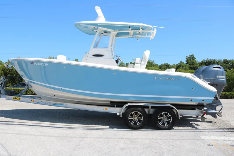Slide: The Image of 2023 Cobia 240 CC boat on trailer, blue hull, Yamaha outboard engine. - 1