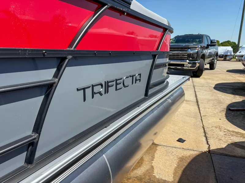 Slide: The Image of 2025 Trifecta 22RF CS boat with red and gray design, parked outdoors. - 6