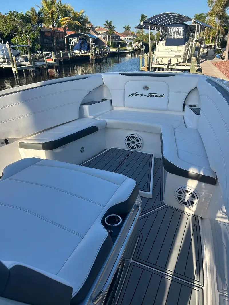 Slide: The Image of 2018 Nor-Tech 340 Sport boat with white seating, docked in a sunny marina. - 11