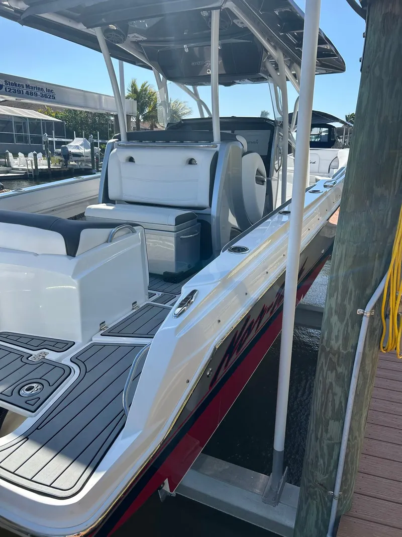 Slide: The Image of 2018 Nor-Tech 340 Sport boat docked, featuring sleek design and spacious seating. - 13