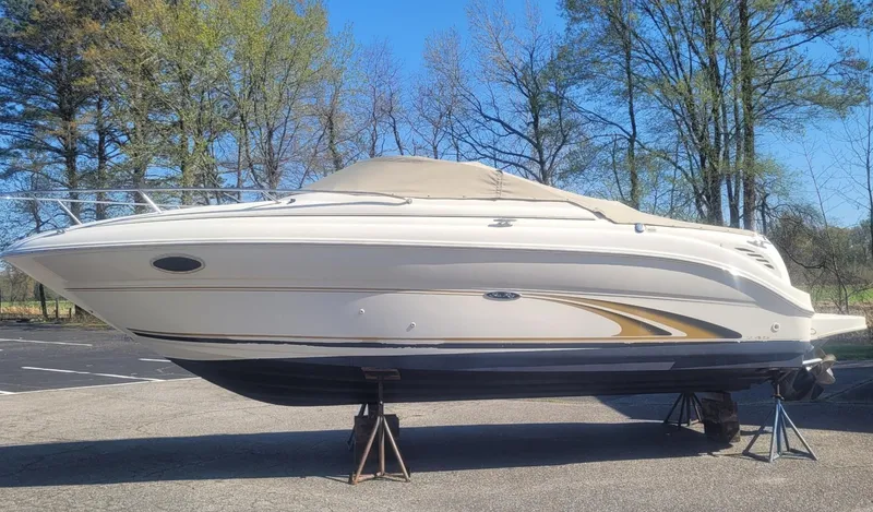 The Image of 2001 Sea Ray 245 Weekender boat on stands, surrounded by trees. - 0