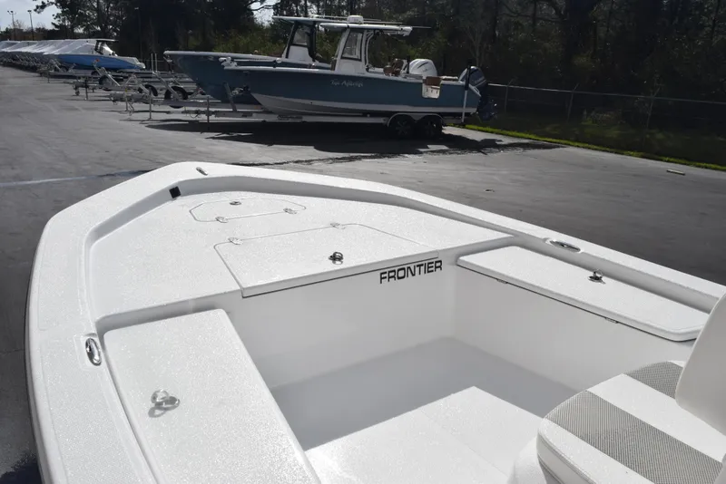 Slide: The Image of 2025 Frontier 2104 boat, white deck, parked outdoors, with other boats in the background. - 11