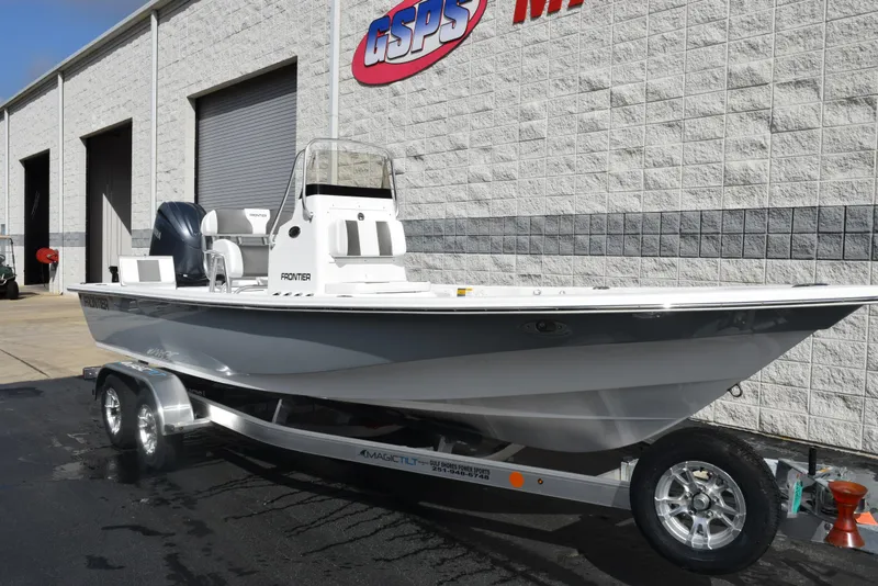 Slide: The Image of 2025 Frontier 2104 boat on trailer outside dealership, white exterior, modern design. - 2