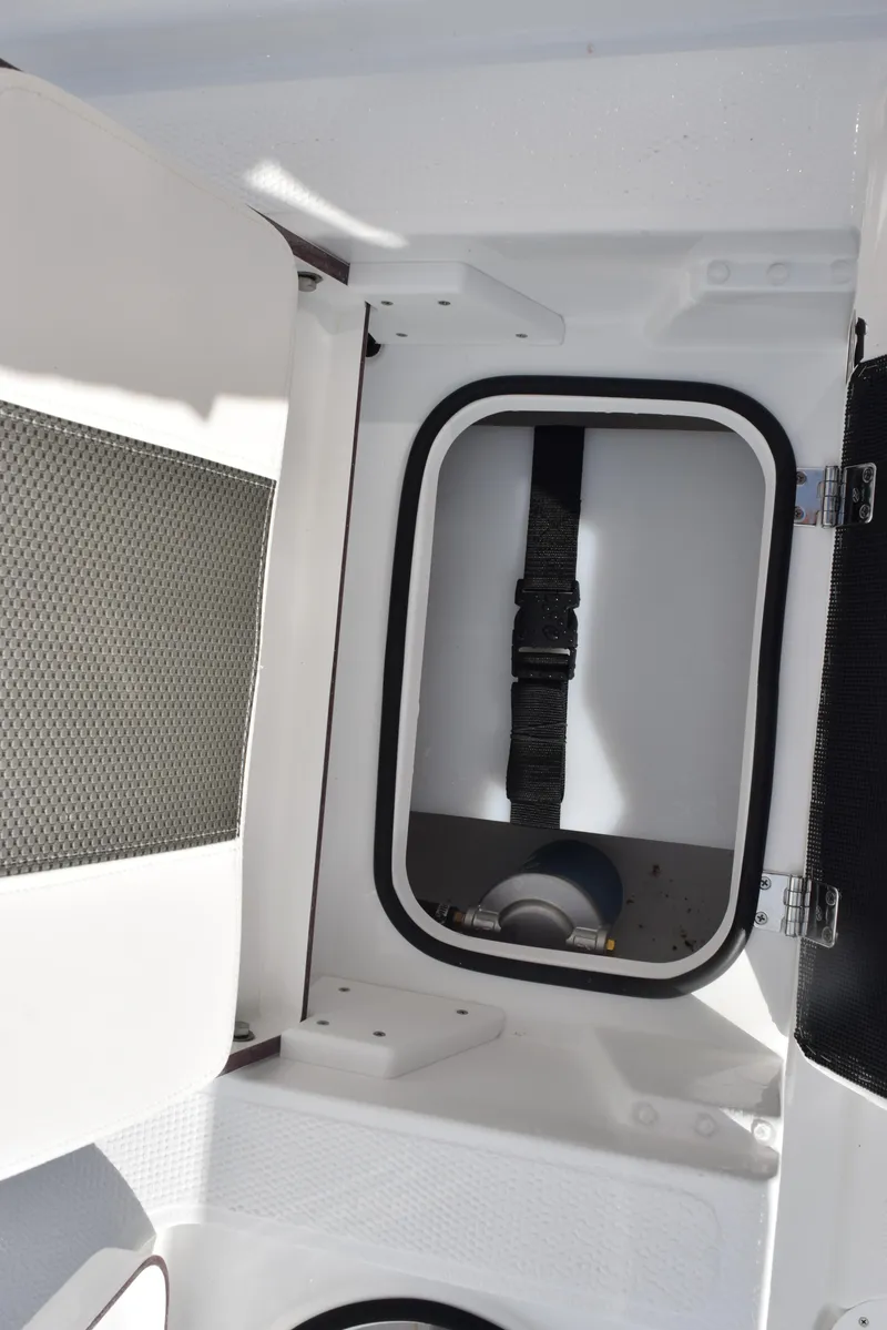 Slide: The Image of 2025 Frontier 2104 boat storage compartment with secure strap and white interior. - 21