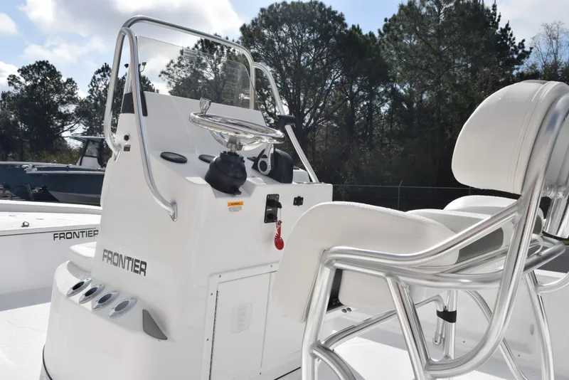 Slide: The Image of 2025 Frontier 2104 boat console with steering wheel and seating, set against a wooded backdrop. - 7