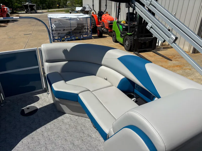 Slide: The Image of 2025 Trifecta 22 RF LE pontoon boat with blue and gray seating, docked outdoors. - 11