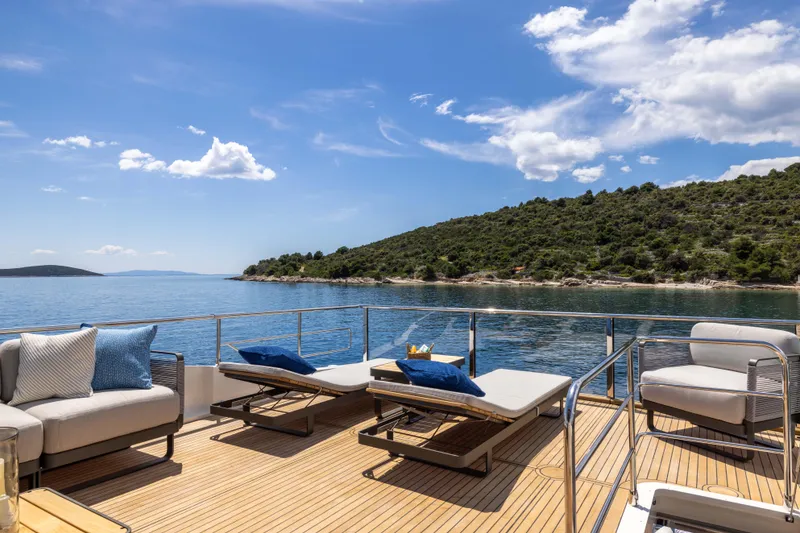 Slide: The Image of Luxurious 2026 Absolute Navetta yacht deck with sun loungers, scenic ocean view, and clear skies. - 28