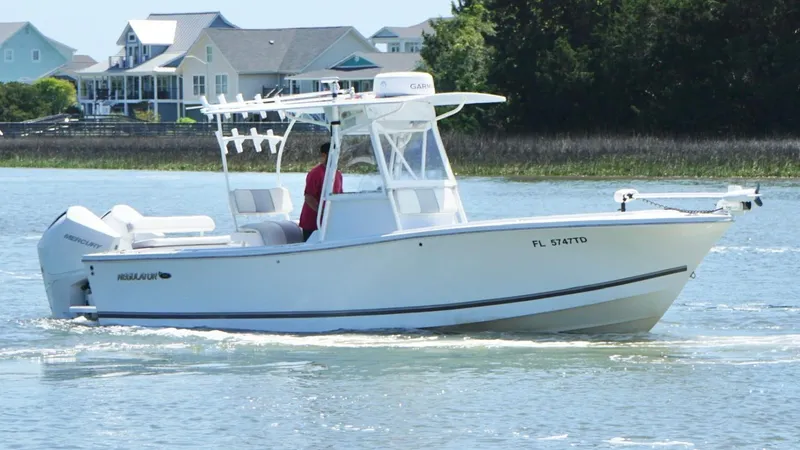 Slide: The Image of 2000 Regulator 26 Classic boat cruising on a calm waterway near coastal homes. - 10