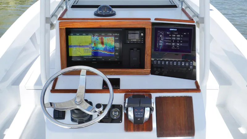 Slide: The Image of Control panel of a 2000 Regulator 26 Classic boat with navigation screens and steering wheel. - 14