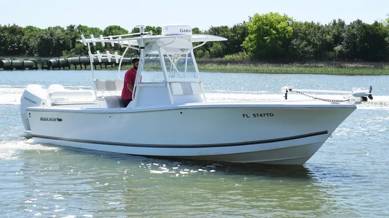 Slide: The Image of 2000 Regulator 26 Classic boat cruising on a calm river with lush greenery. - 3