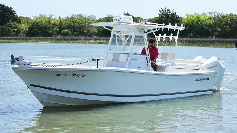 Slide: The Image of 2000 Regulator 26 Classic boat cruising on calm water with a person onboard. - 5